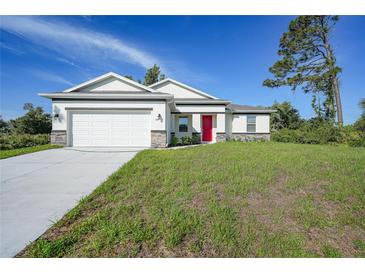 Charming single-Gathering home featuring a two-car garage, well-maintained lawn, and welcoming red front door at 7345 Ellis Ln, Port Charlotte, FL 33981