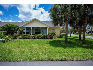 Charming home with a well-manicured lawn, lush landscaping, and inviting front porch with column supports at 1318 Red Oak Ln, Port Charlotte, FL 33948