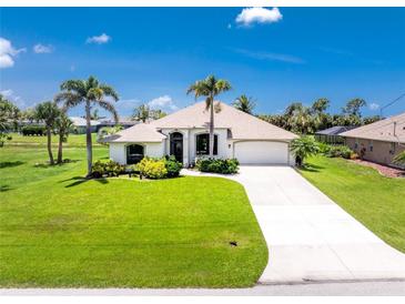 Charming single-story home featuring lush lawn, palm trees and a pristine driveway at 167 & 169 Marker Rd, Rotonda West, FL 33947