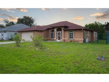 Tan single-story home featuring arched windows and a well-maintained front lawn at 23101 Hillsdale Ave, Port Charlotte, FL 33954