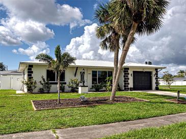 Charming single-story home with black and white accents, beautiful landscaping, and lush palm trees at 6483 Fabian Rd, North Port, FL 34287