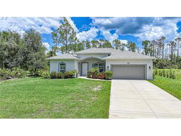 Charming single-story home with a well-manicured lawn, lush landscaping, and a neutral color scheme at 1722 Amnesty Dr, North Port, FL 34288