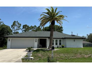 Charming single-story home featuring a well-maintained lawn and a stately palm tree at 21287 Birwood Ave, Port Charlotte, FL 33954