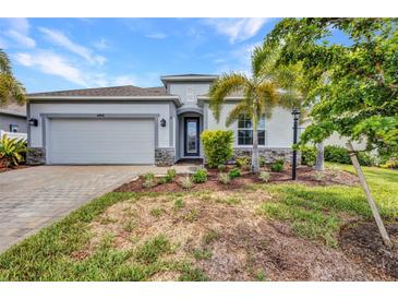 Beautiful one-story home with a two-car garage, well-manicured lawn, and stone accents at 16848 Canopy Garden Dr, Port Charlotte, FL 33953