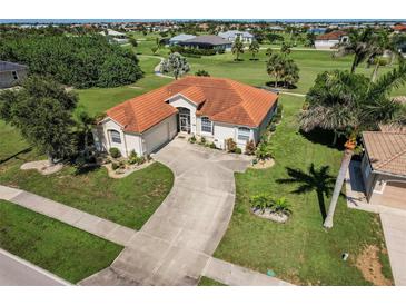Aerial view of a home with a tile roof, long driveway, and lush landscaping on a sunny day at 2105 Deborah Dr, Punta Gorda, FL 33950