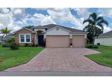 Charming single-story home with a stone facade and a three-car garage and a beautifully paved brick driveway at 25224 Lahore Ln, Punta Gorda, FL 33983