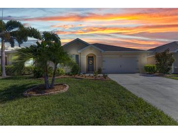 Inviting single-story home featuring a well-manicured lawn, tasteful landscaping, and a warm, neutral color palette at 25272 E Lenox Cir, Punta Gorda, FL 33950