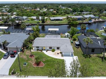 Waterfront home featuring a private dock with a boat lift, lush landscaping, and a well-maintained yard at 4051 Rock Creek Dr, Port Charlotte, FL 33948