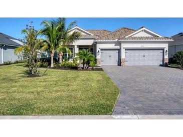 Charming one-story home featuring a tile roof, brick driveway, lush landscaping, and a two-car garage at 14436 Ponce De Leon Trl, Port Charlotte, FL 33981