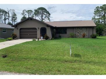 Charming single-story home featuring an attached garage and well-maintained lawn at 18094 Ackerman Ave, Port Charlotte, FL 33948