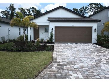 Charming single-story home with a well-manicured lawn, brick driveway, and attached two-car garage at 1992 Sunset Preserve Way, Port Charlotte, FL 33953