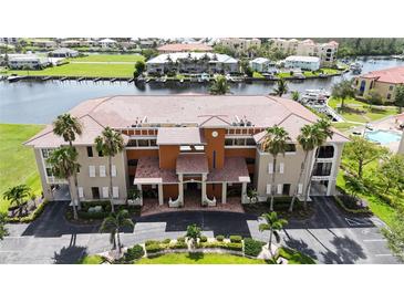 Beautiful condo building with terracotta tile roof, palm trees, manicured lawn, and views of the bay at 3308 Purple Martin Dr # 121, Punta Gorda, FL 33950