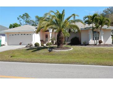 Charming single-story home featuring a well-manicured lawn, mature palm trees, and a two-car garage at 388 Orlando Blvd, Port Charlotte, FL 33954
