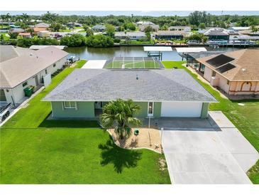 Waterfront home with a well-manicured lawn, mature palm tree, and a screened lanai for seamless indoor-outdoor living at 4123 Rock Creek Dr, Port Charlotte, FL 33948