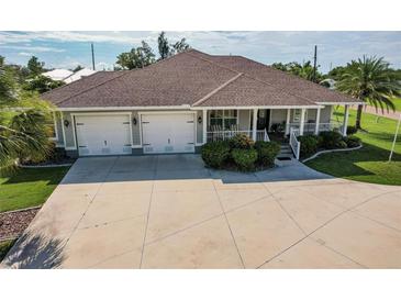 Beautiful single-story home featuring a two-car garage, covered front porch, manicured landscaping and spacious driveway at 437 South Dr, Punta Gorda, FL 33950