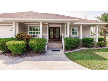Charming front porch with decorative columns, lush landscaping, and a welcoming entrance at 437 South Dr, Punta Gorda, FL 33950