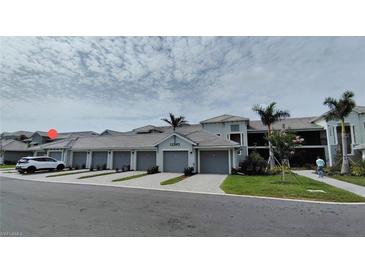 Condominium exterior with private garages, tropical landscaping, and paver driveway under partly cloudy skies at 12390 Wellen Golf St # 202, Venice, FL 34293