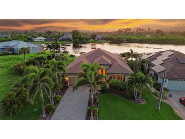Stunning waterfront home with lush landscaping, paver driveway, and breathtaking sunset views over the lake at 170 Antilla Dr, Rotonda West, FL 33947