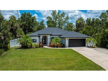 Charming single-story home featuring a well-manicured lawn and lush landscaping at 3824 Dominic St, North Port, FL 34288