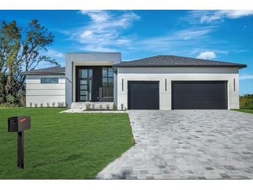 Stunning modern home with a two-car garage, clean lines, and beautiful stone driveway at 44 Sunflower Dr, Placida, FL 33946