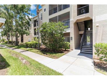 Tan condo building featuring outdoor stairwell, landscaped grounds, and sidewalks at 5146 Northridge Rd # 305, Sarasota, FL 34238