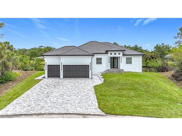 Beautiful new construction home with a paver driveway, two-car garage, and lush landscaping at 576 Mcdill Dr, Port Charlotte, FL 33953