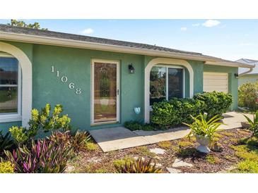 Inviting home entrance with vibrant foliage, glass door and decorative house numbers at 11068 Jacqueline Ave, Englewood, FL 34224