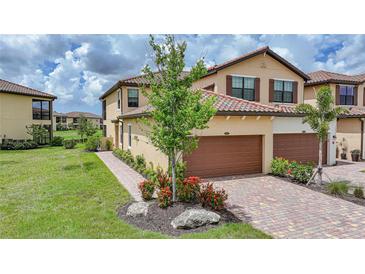 Beautiful two-story home featuring a well-manicured lawn, brick driveway, and an attached two-car garage at 12425 Ghiberti Cir # 101, Venice, FL 34293