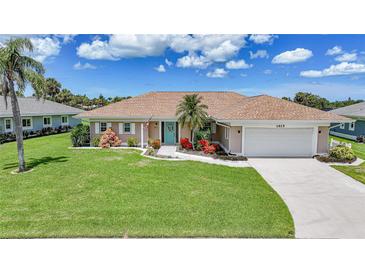 Charming single-story home with a well-manicured lawn and a welcoming turquoise front door at 1915 Pebble Beach Ct, Venice, FL 34293