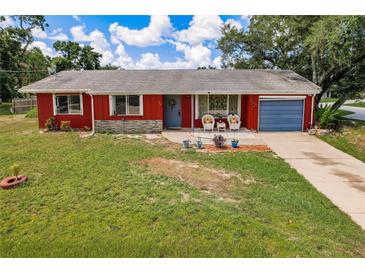 Charming single-story home features a vibrant red exterior, blue garage door, and well-maintained lawn at 20409 Emerald Ave, Port Charlotte, FL 33952