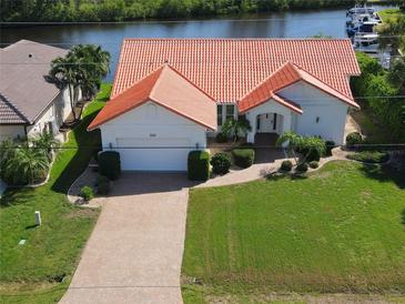 Beautiful waterfront home featuring a red tile roof, attached garage, and lush landscaping at 3588 Tripoli Blvd, Punta Gorda, FL 33950