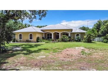 Charming single-story home with a metal roof and lush landscaping at 6594 Buckboard St, North Port, FL 34291