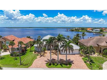 Stunning waterfront home with lush landscaping, brick driveway, and picturesque water views at 119 Creek Se Dr, Port Charlotte, FL 33952