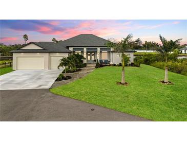 Beautiful single-story home featuring a lush lawn, two-car garage and a covered entryway with decorative wreaths at 12581 Eisenhower Dr, Port Charlotte, FL 33953