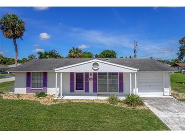 Charming single story home with purple shutters, an attached garage, and a well-maintained front lawn at 1389 Hinton St, Port Charlotte, FL 33952