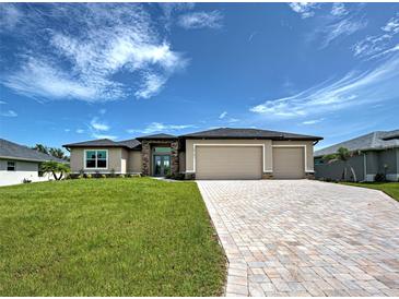 Charming single-story home with a three-car garage, beautiful stone accents, and a well-manicured lawn at 15741 Autry Cir, Port Charlotte, FL 33981