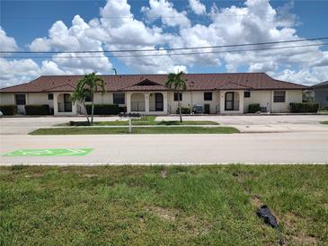 Low-rise condo building with beige stucco and terra cotta tile roof, palm trees and lush green landscaping at 2732 Magdalina Dr # C, Punta Gorda, FL 33950