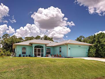 Charming single-story home with turquoise exterior, manicured lawn, and attached two car garage beneath a partly cloudy sky at 2969 Wells Ave, North Port, FL 34286