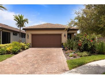 Charming single Gathering home featuring a tile roof, brick driveway, and lush landscaping at 13935 Campoleone St, Venice, FL 34293