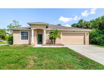 Inviting single-story home with a well-manicured lawn and a two-car garage in a sunny, tropical setting at 1693 Jagust Rd, North Port, FL 34288