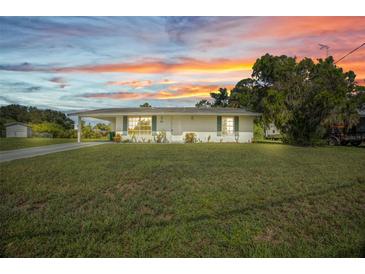 Charming single-story home featuring a well-maintained lawn and inviting curb appeal at sunset at 769 Crestview Nw Cir, Port Charlotte, FL 33948