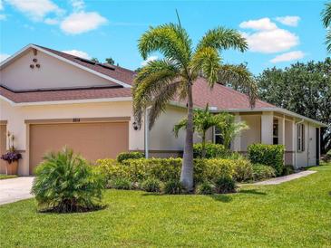 Charming home featuring a well-manicured lawn, lush landscaping, and a two-car garage at 8814 Tuscany Isles Dr, Punta Gorda, FL 33950
