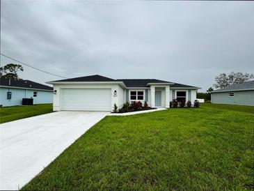 Charming single-story home featuring a well-manicured lawn, a two-car garage, and colorful landscaping at 8917 Sawyer Cir, North Port, FL 34288