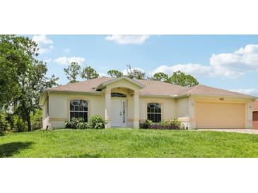 Charming single-story home featuring a manicured lawn, attached two car garage, and welcoming front entrance at 5260 Jessamine Ave, North Port, FL 34291