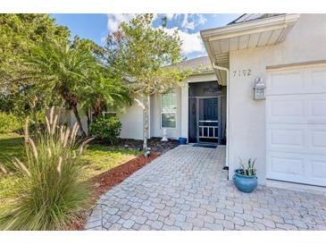 Charming home featuring a paved walkway, lush landscaping, and a welcoming screened entrance at 7192 N Paragon Rd, North Port, FL 34291