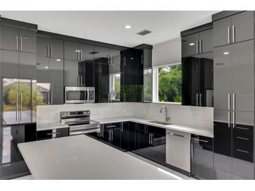 Modern kitchen with black cabinets and white countertops at 118 Green Pine Park, Rotonda West, FL 33947