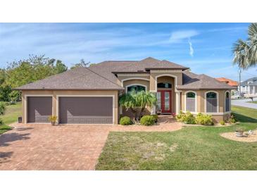 One-story house with two-car garage, lush landscaping and brick paver driveway at 9303 Migue Cir, Port Charlotte, FL 33981
