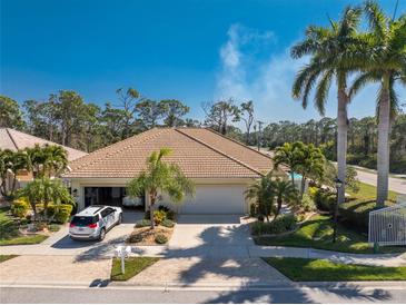 Exterior view of a single story house with a tan facade and lush landscaping at 28260 Pablo Picasso Dr, Englewood, FL 34223