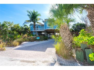 Elevated waterfront home with a light blue exterior, palm trees, and a paved driveway at 431 Kettle Harbor Dr, Placida, FL 33946