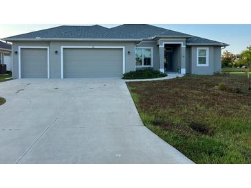 Three-car garage gray house with a large front yard at 48 Long Meadow Ln, Rotonda West, FL 33947